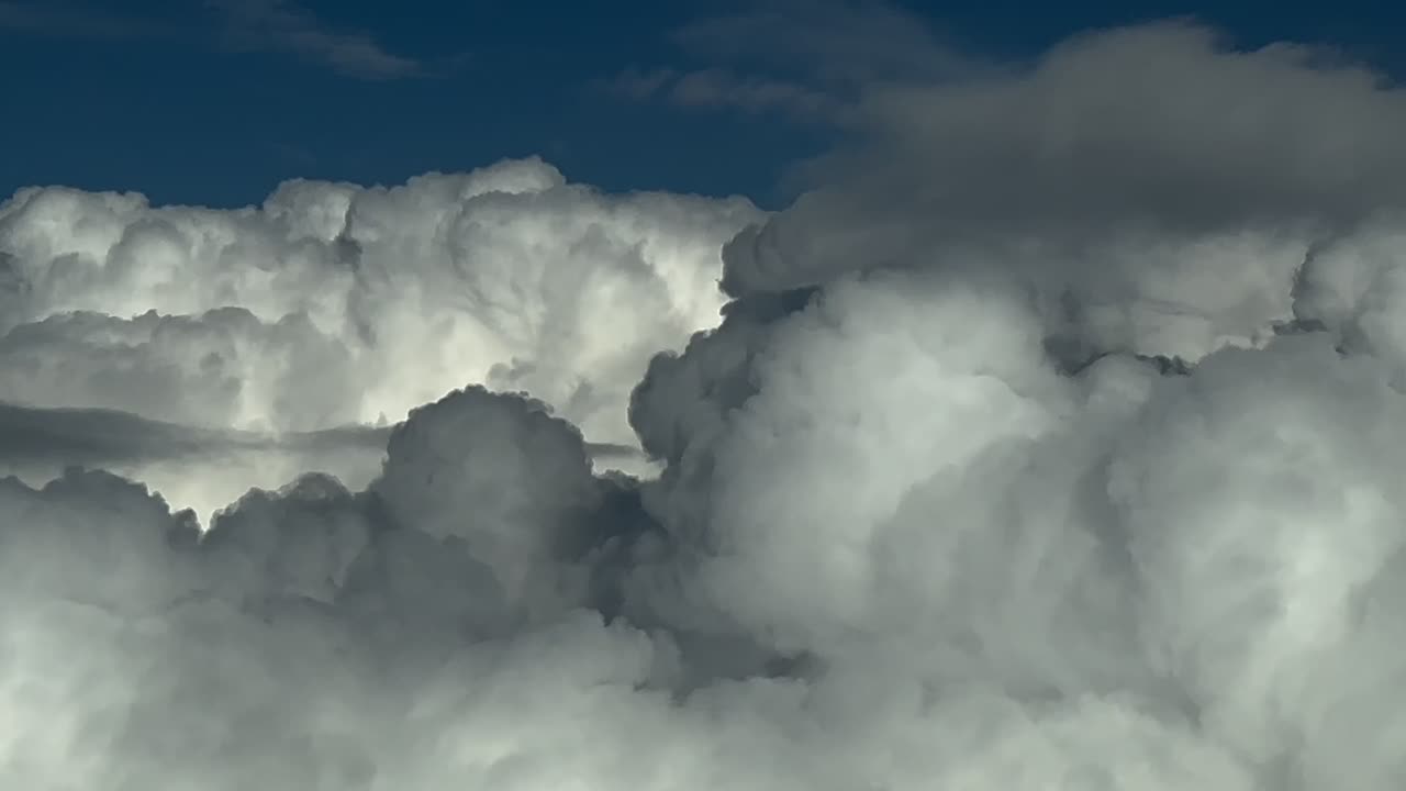 Left side aerial view shot from a jet cockpit flying through a stormy sky full of storm clouds. 4K 60FPS