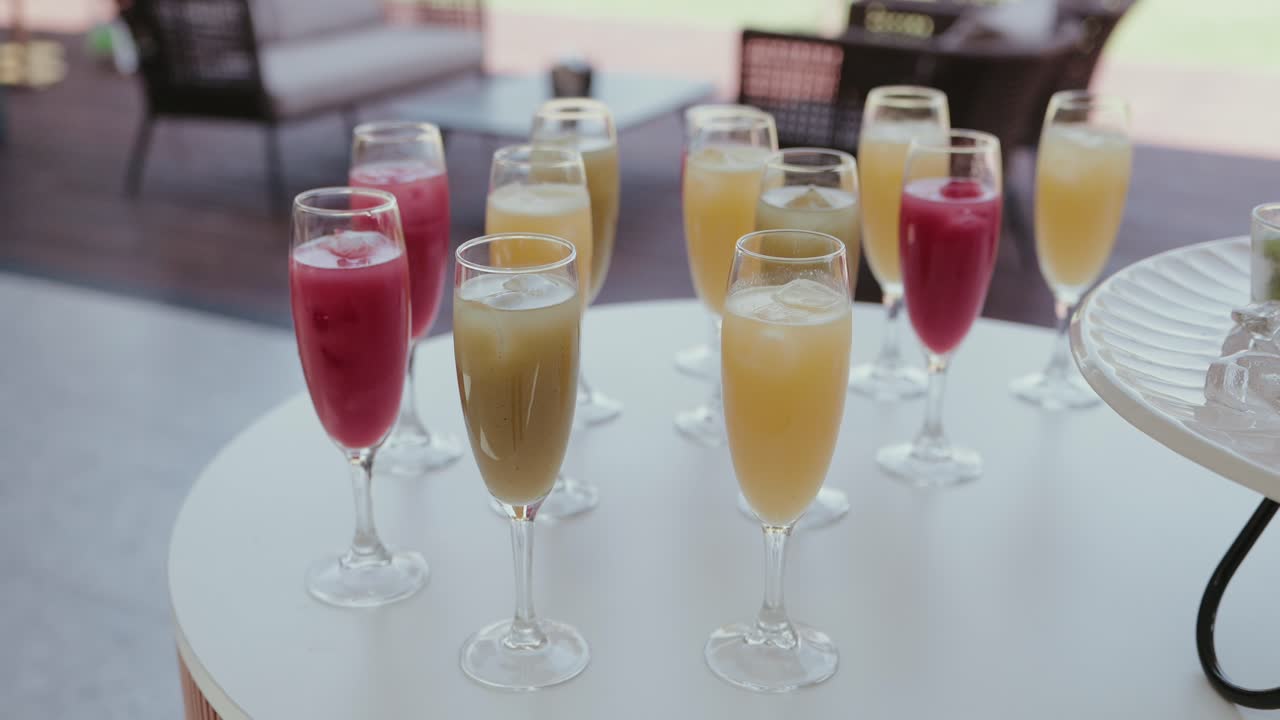 Variedade de coquetéis vermelhos e amarelos em taças de champanhe com gelo sobre uma mesa
