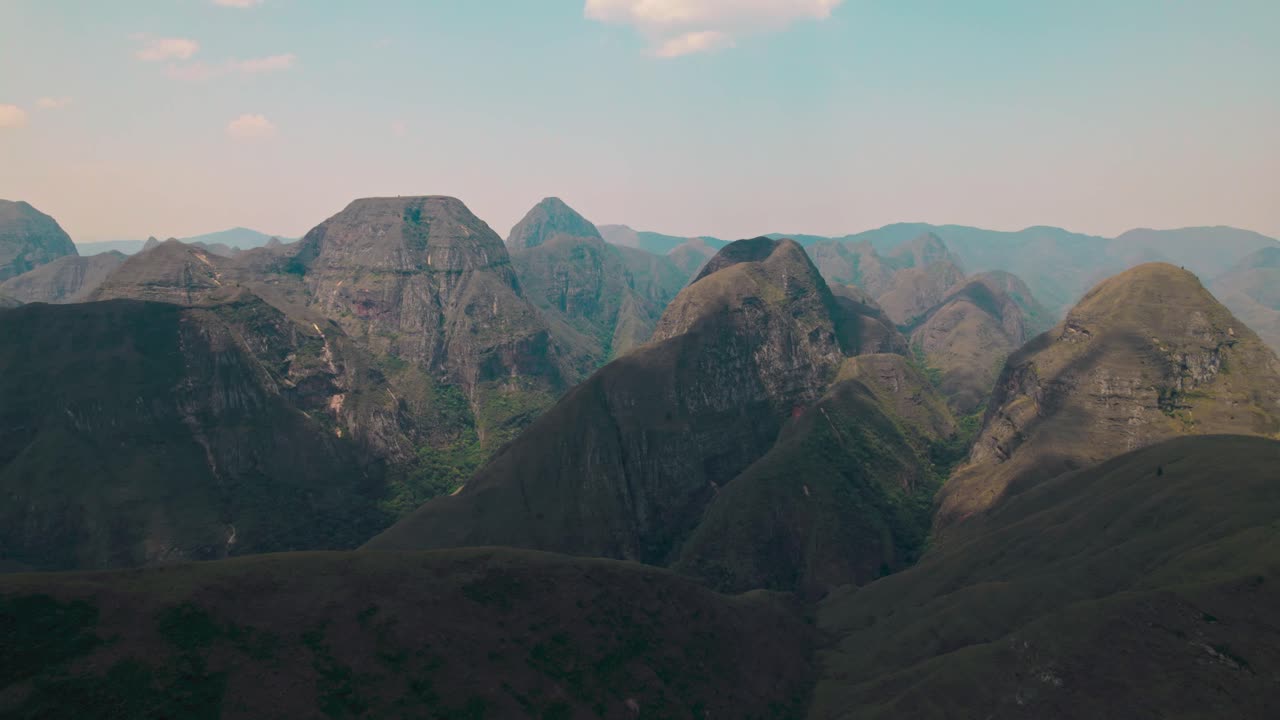 A breathtaking wide aerial or drone shot capturing the vast, rugged, and majestic landscape of the Codo de los Andes mountain range in Bolivia under a clear blue sky, emphasizing natural beauty