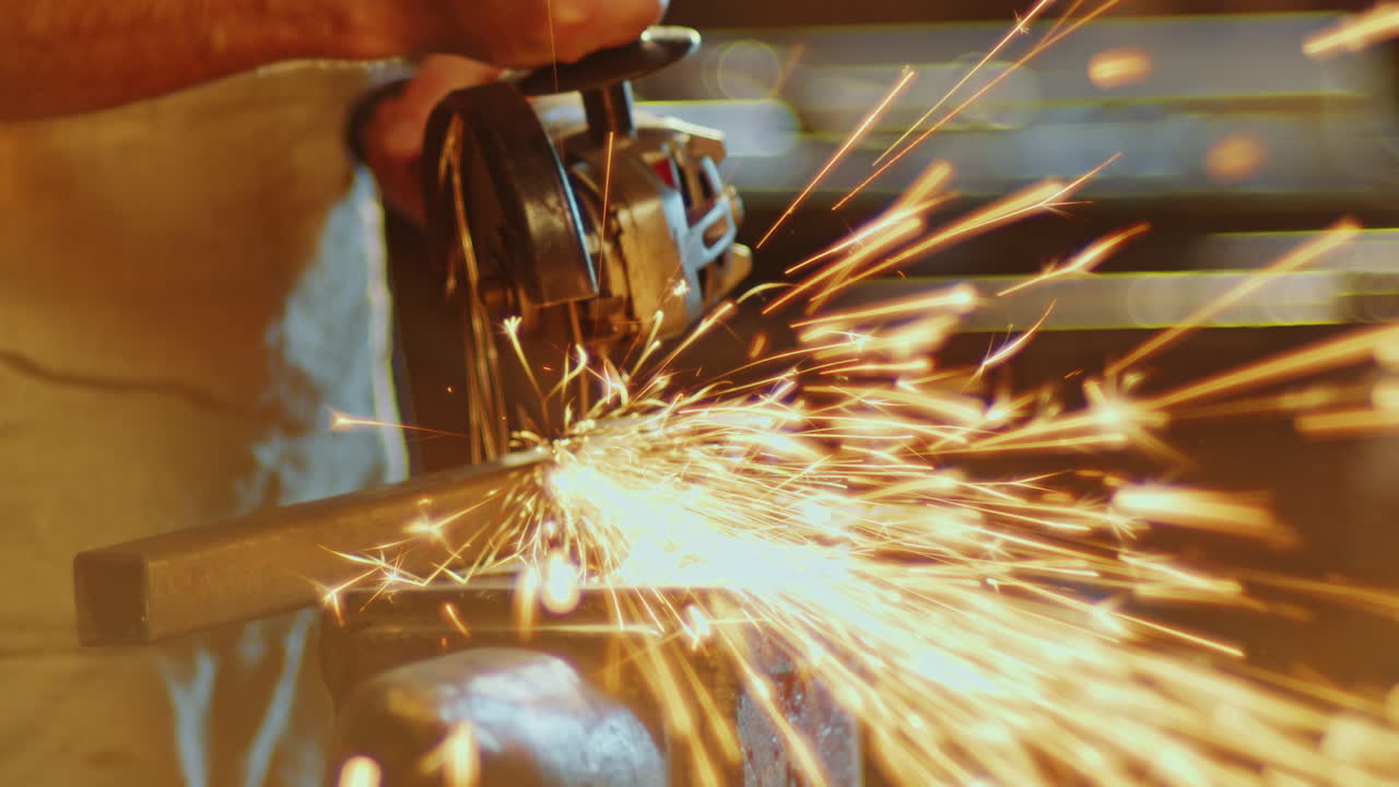 человек, разрезающий металлический предмет с помощью угловой шлифовальной машины в кузнеце