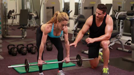 woman lifting barbell with her trainer at crossfit session