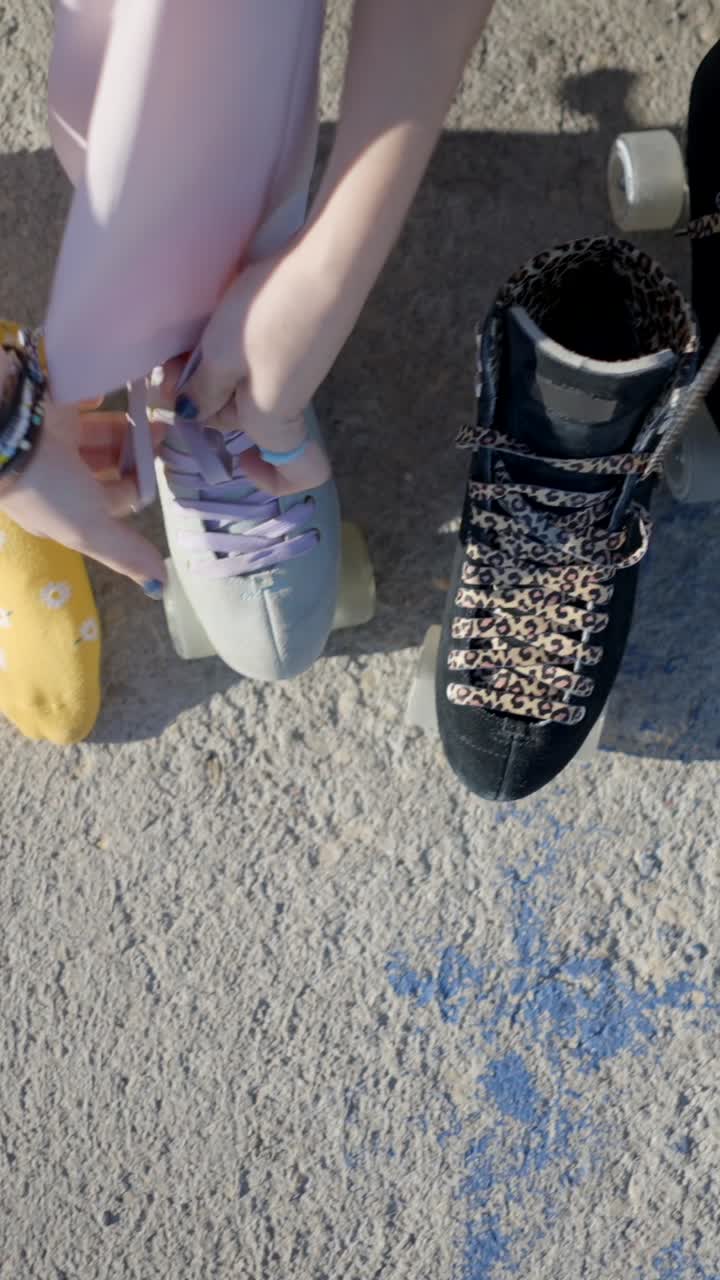 Close-up of people tying roller skate laces on concrete