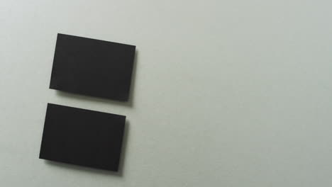 vista aérea de dos tarjetas de visita negras dispuestas en fondo gris, espacio de copia, cámara lenta