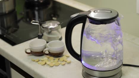 tea kettle with boiling water. tea bags and sugar on the background