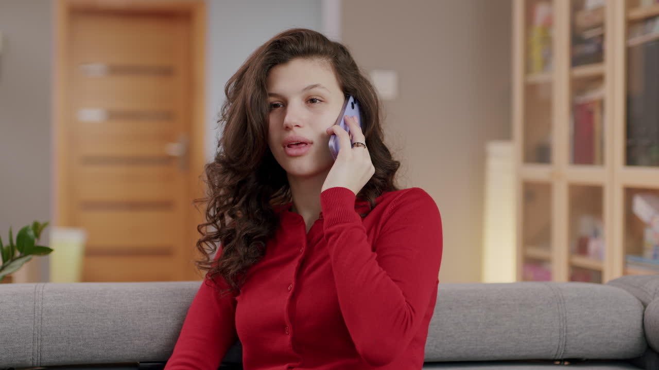 joven mujer feliz de cabello oscuro habla por teléfono en la sala de estar, slomo
