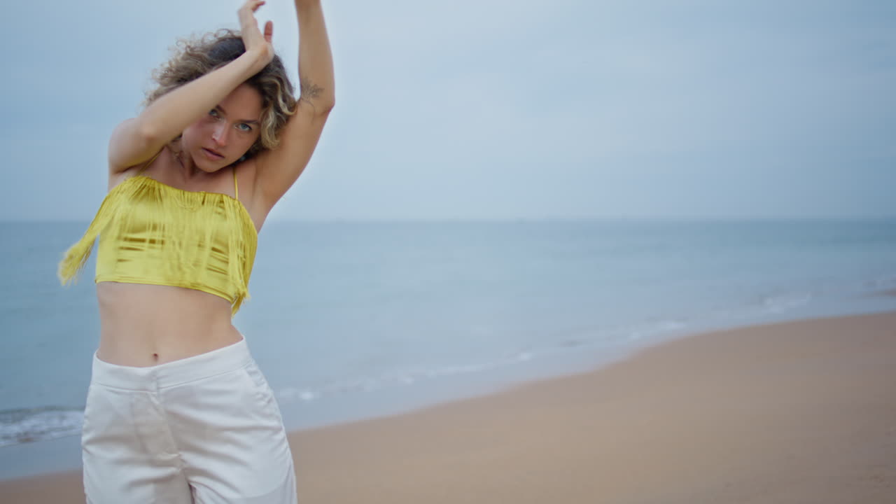 트렌디한 옷을 입고 모래 해변에서 프리스타일을 하는 멋진 댄서 여성 클로즈업