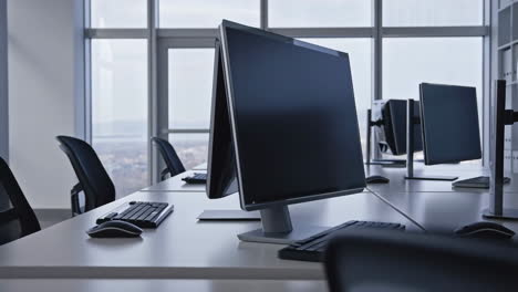 empty modern office workspace with multiple computer workstations and large windows