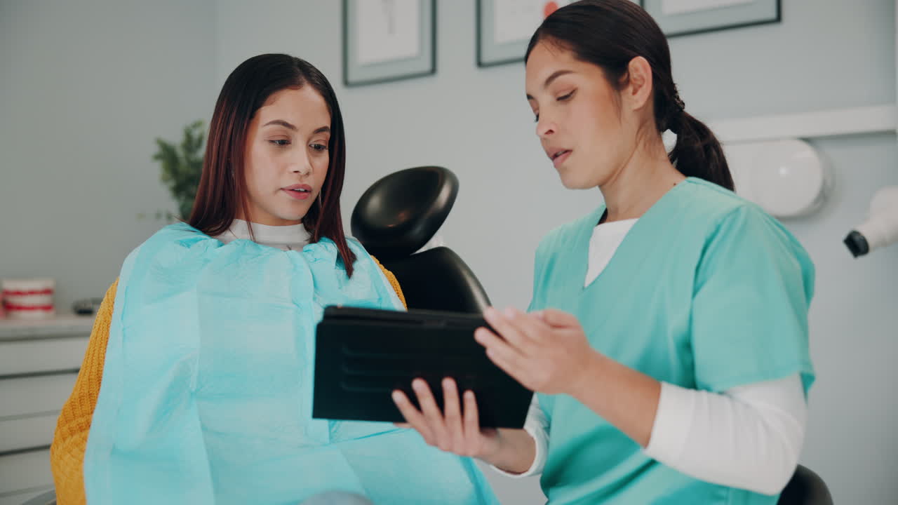 dentista y paciente discutiendo los registros dentales en la tableta