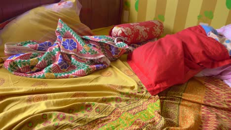 messy bed with colorful pillows and sheets