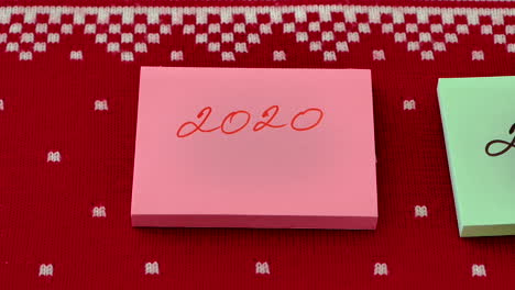 hand moving post-it note stack with another with change of year against red design background