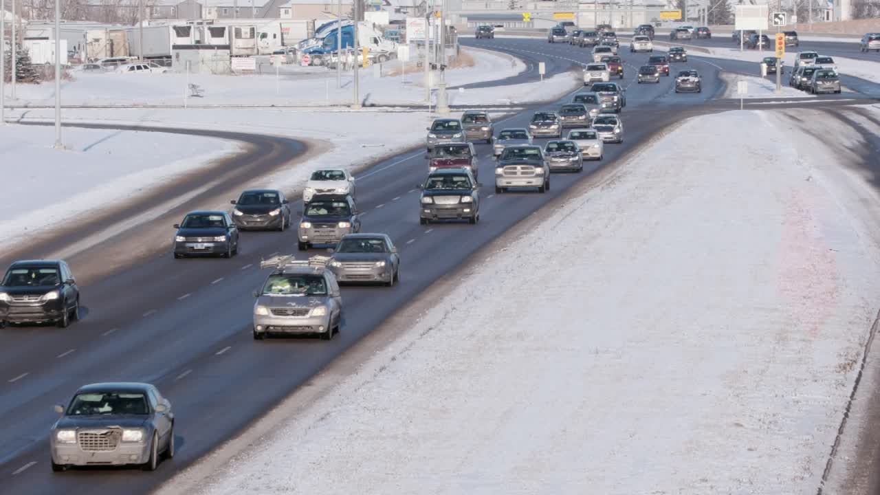 Cold vehicles slowly advance through suburban intersection in winter