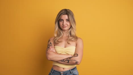 unhappy young woman standing with crossed hands on yellow background