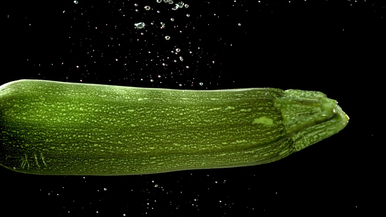 Zucchine verdi fresche che galleggiano nell'acqua con bolle d'aria