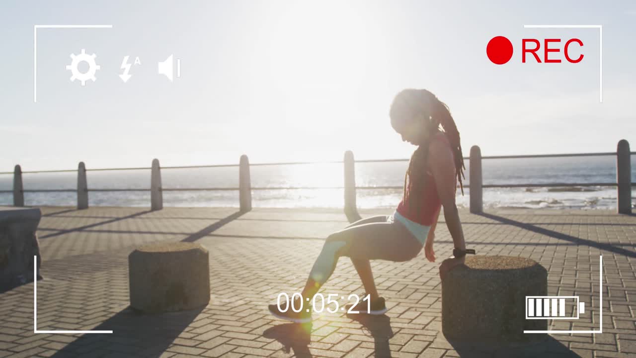 Digital camera interface against tired african american fit woman sitting on the promenade