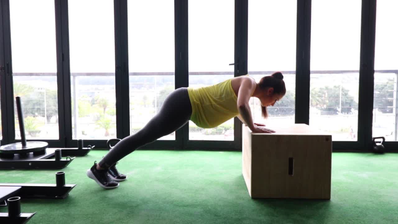 modelo de fitness femenino embarazada haciendo ejercicio de peso corporal en un gimnasio para mantenerse en forma durante su tercer trimestre de embarazo