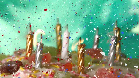 colorful confetti falling over burning candles on cake against green background