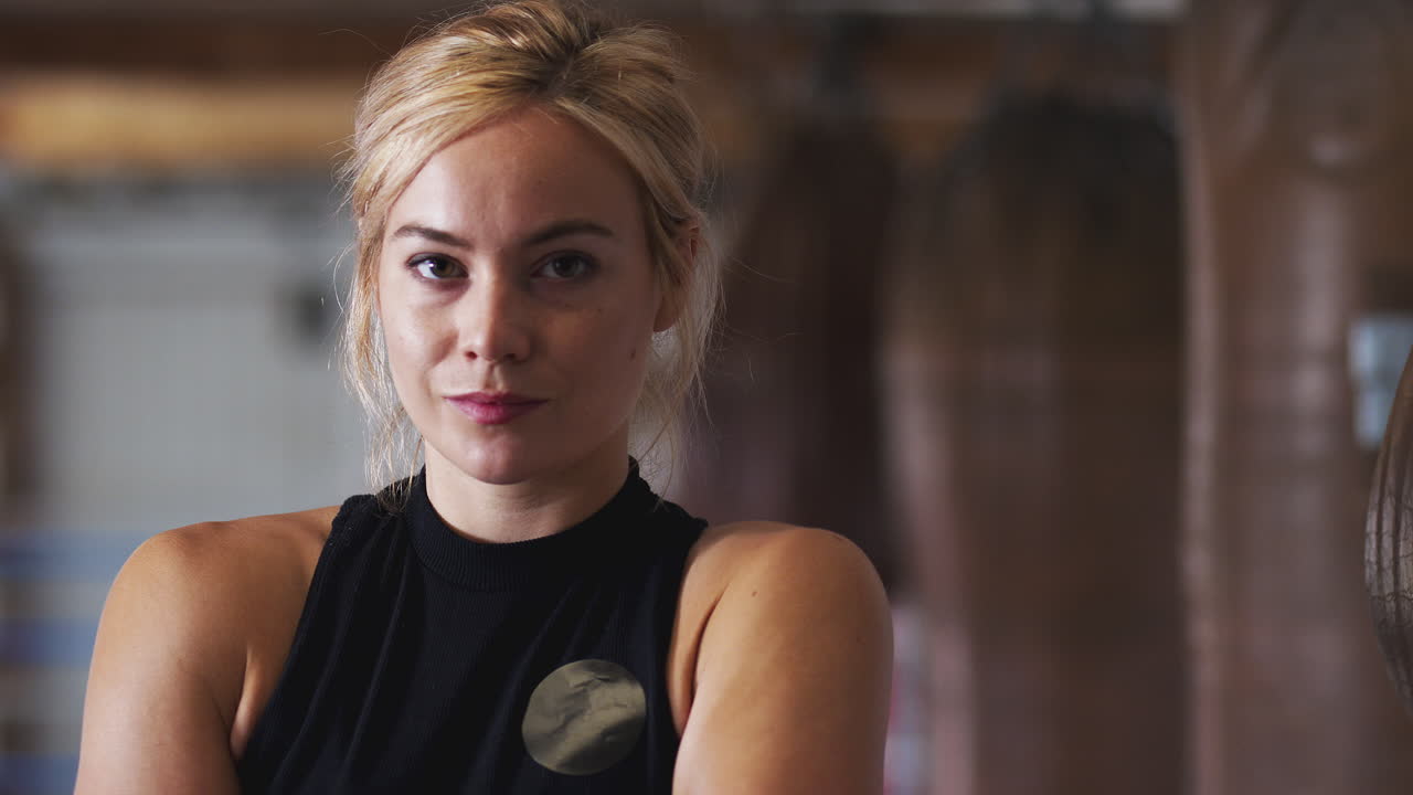Ritratto di pugile donna in palestra che si allena con sacchi da boxe vecchio stile