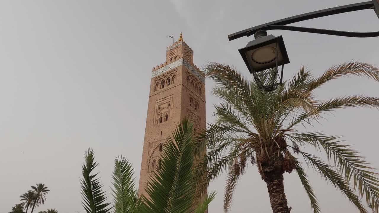 mirando hacia arriba a la torre de la mezquita de koutoubia detrás de la lámpara marroquí y las palmeras