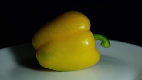 dando la vuelta expuesto en un plato revelando la frescura de este vegetal listo para ser cocinado o añadido en una ensalada, pimienta amarilla