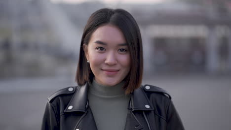 portrait of young pretty woman smiling and looking at camera outdoors