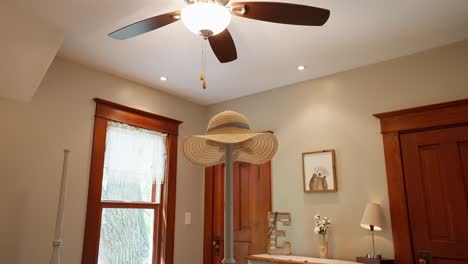 push-in-shot-of-a-sun-hat-sitting-on-a-bed-frame-pole-in-a-bedroom