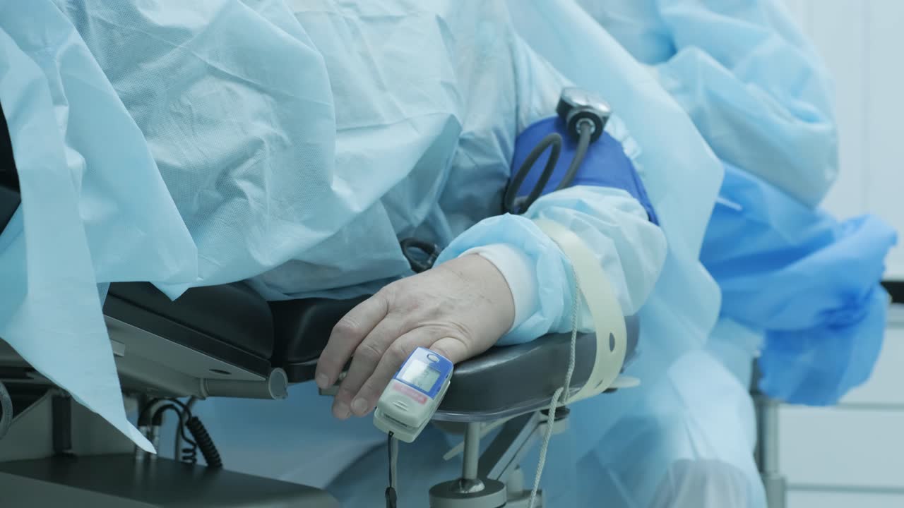 Vecchio paziente con pulsossimetro sul dito per il monitoraggio durante l'intervento chirurgico in ospedale