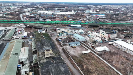huge industrial territory abandoned long ago. aerial view of old ruined warehouses near railways and trains. city view at the backdrop.