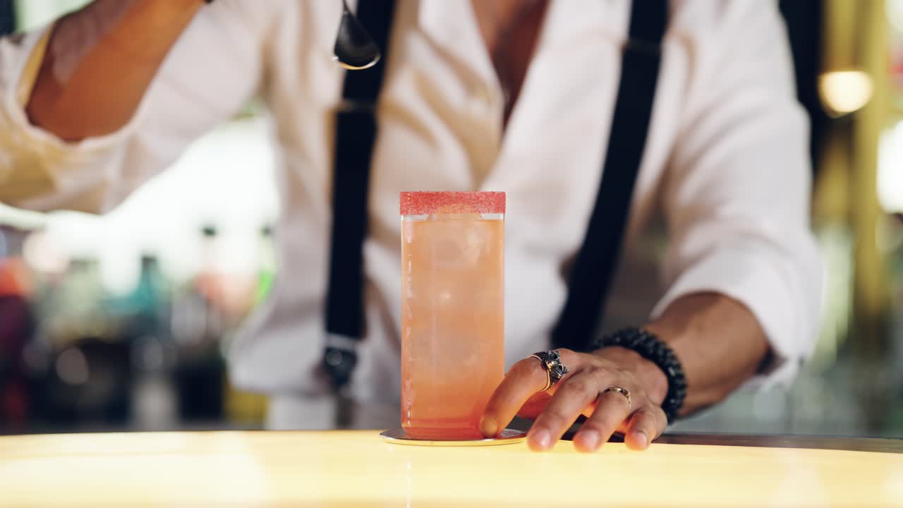 Bartender Stirring a Refreshing Pink Cocktail at a Bar Counter