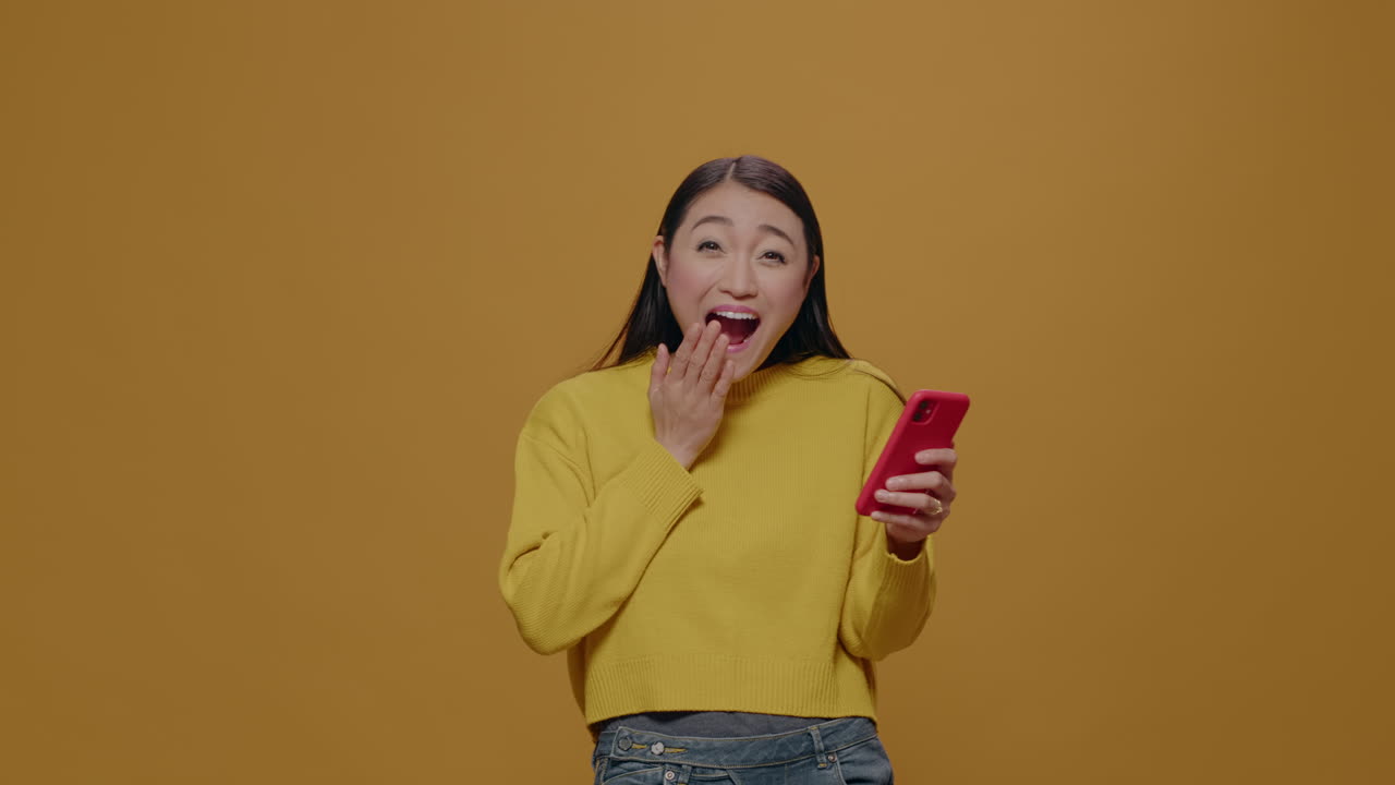 Asian woman feeling happy about good news on mobile phone