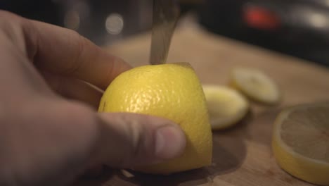 a person hands cutting a yellow lemon on a cutting board - close up shot