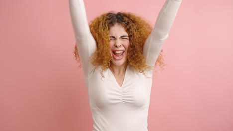 excited woman receiving good news on smartphone on pink background