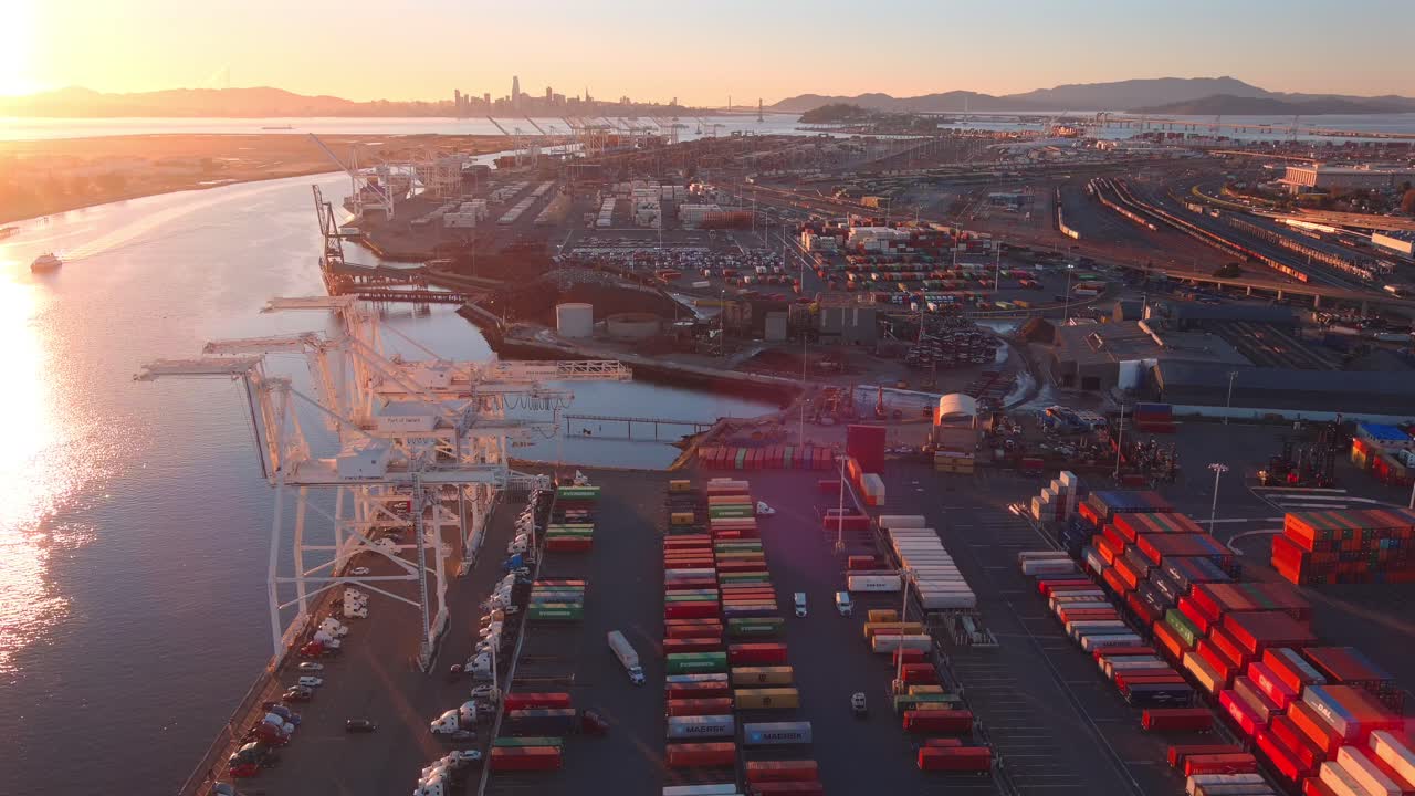Cranes in a large container port at sunset, aerial establishing view