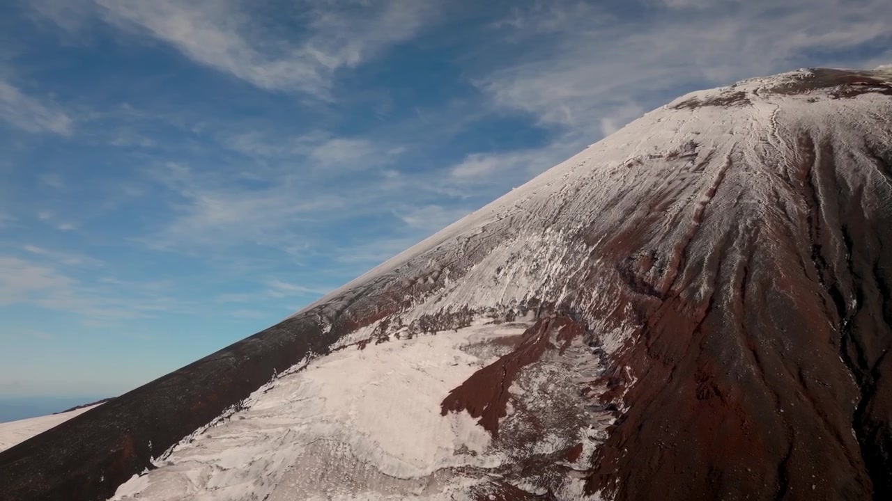 Riprese drone del Vulcano Avachinsky con cratere innevato e scuri pendii di cenere vulcanica sotto un cielo blu, Territorio della Kamchatka, Russia, paesaggio selvaggio e remoto