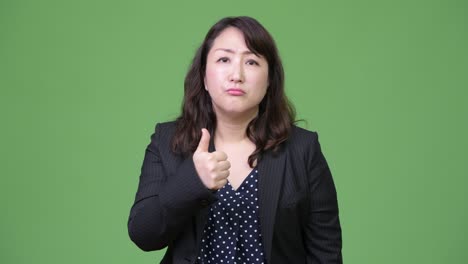 mature tired asian businesswoman giving thumbs up