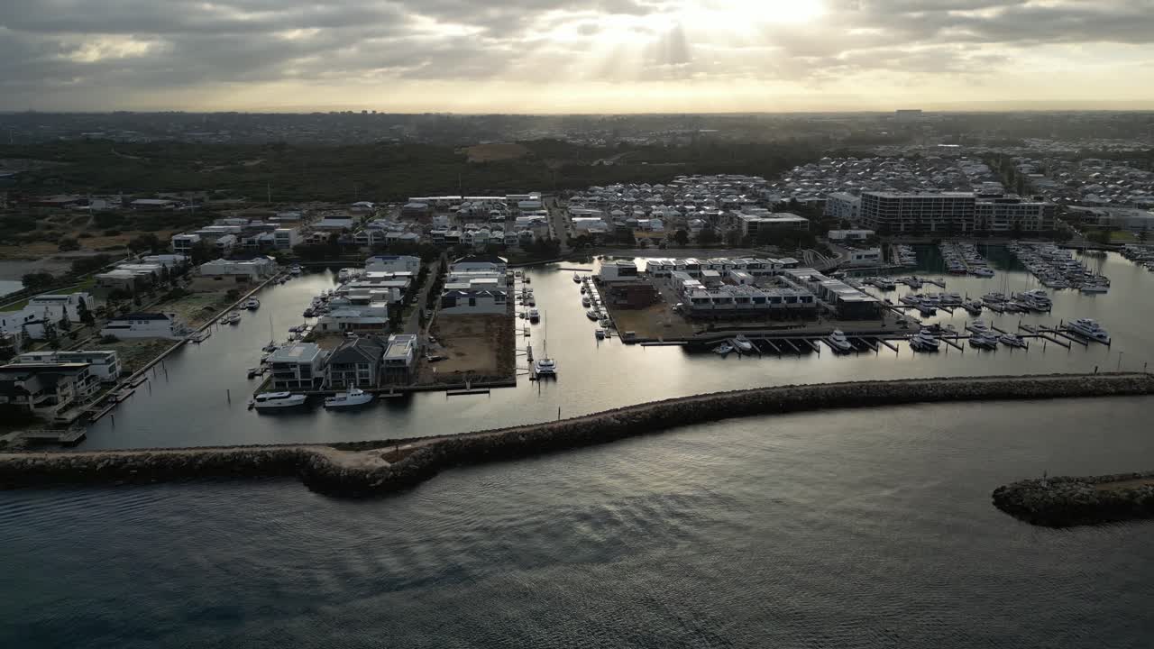 vista aérea que muestra el puerto deportivo de coogee en la ciudad de perth con barcos y yates estacionados a la hora de la puesta del sol - paisaje urbano en australia occidental en el fondo - tiro de senderismo