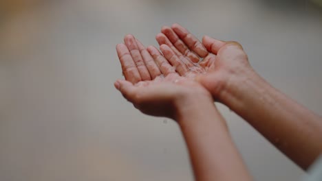 close-up of indian village girl’s hands stretched out into the falling rain, feeling the droplets, peaceful monsoon moment, 4k video
