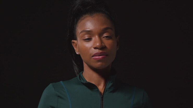 Portrait Of Determined Female Athlete Wearing Tracksuit Training And Preparing Psychologically For Sports Event Against Black Studio Background