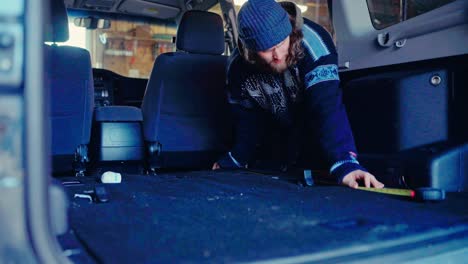 a man measures the pajero’s interior in preparation for a makeover - close up