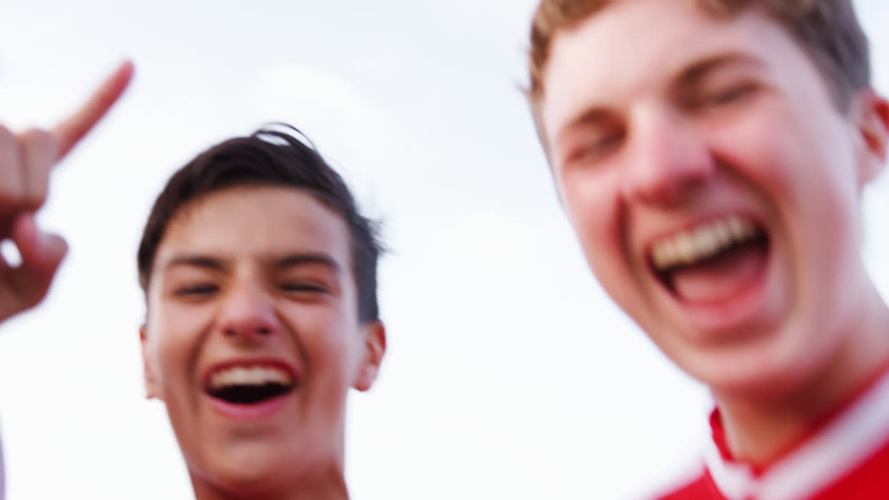 retrato del equipo de fútbol masculino de la escuela secundaria corriendo hacia la cámara y celebrando