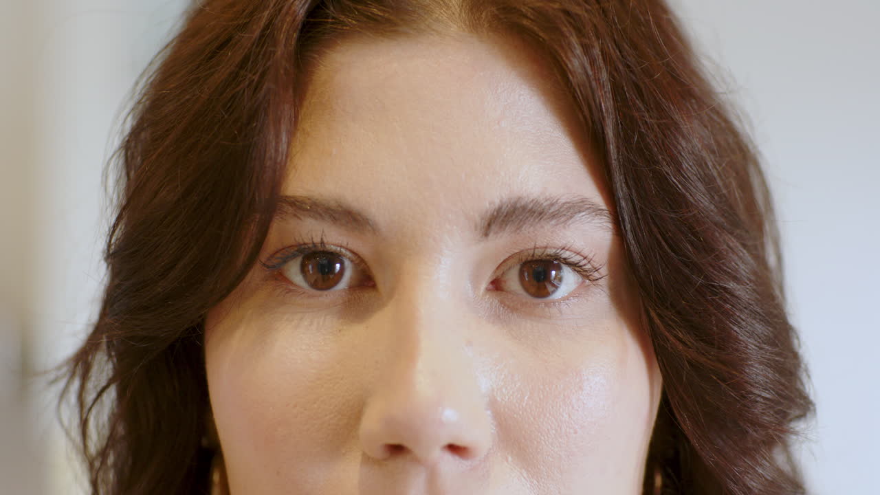 Close-up of woman's eyes, expressing calm and focus, with soft lighting, at home