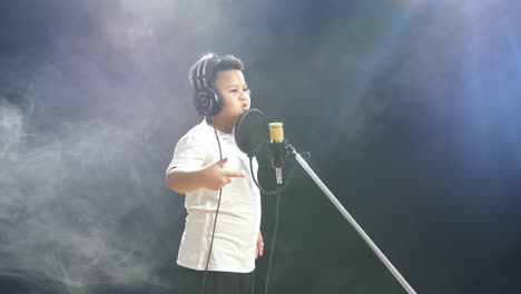 young boy singing into a microphone in a recording studio