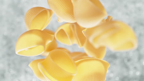 pipe rigate pasta falling into pot of boiling water making a splash in slow motion, table top view