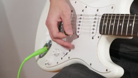 a medium shot of a man playing guitar solos, chords and rhythm with bass in a studio focussing on the hands