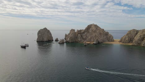 Aerial:-boat-tours-to-famous-Arch-of-Cabo-San-Lucas-in-Mexico,-Baja-Peninsula