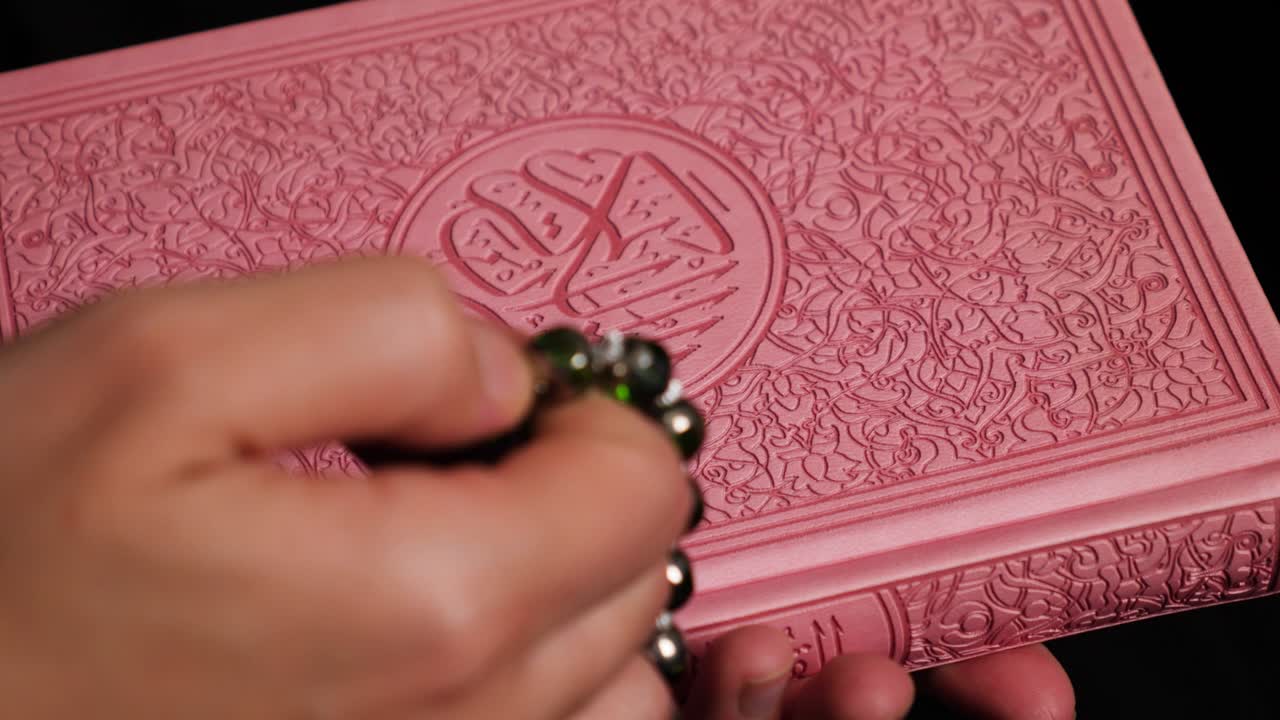 A person doing dhikr on a prayer beads holding the Quran in the other hand