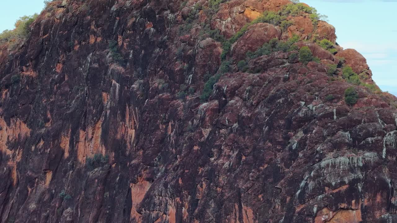 Camera slowly pans past Timor Rock, unveiling expansive bushland under bright natural daylight