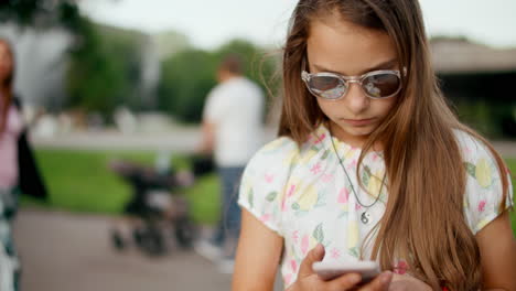 Nahaufnahme-Eines-Ernsthaften-Teenagermädchens,-Das-Im-Sommerpark-Auf-Dem-Smartphone-Surft