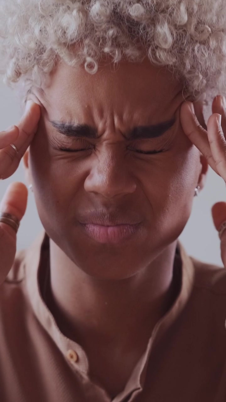Femme afro-américaine stressée se massant les tempes à cause d'un mal de tête intense.