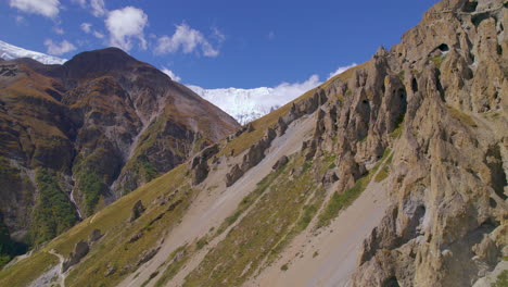 Pleasant-sunny-weather-at-Annapurna-circuit-Nepal,-Drone-shot-of-unique-muddy-structure-hills,-clouds-and-mountain-visible-landscape-4K