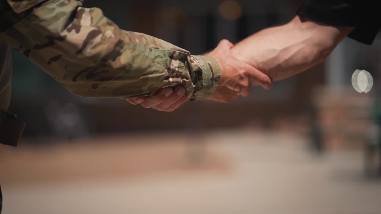 militar y civil agarrando los brazos estrechando la mano cerca de cámara lenta